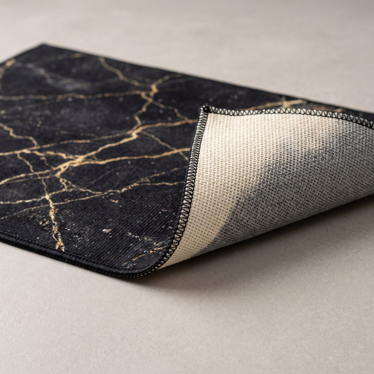 Détail du bord du Tapis de Bain Marbre Nordique Noir Doré