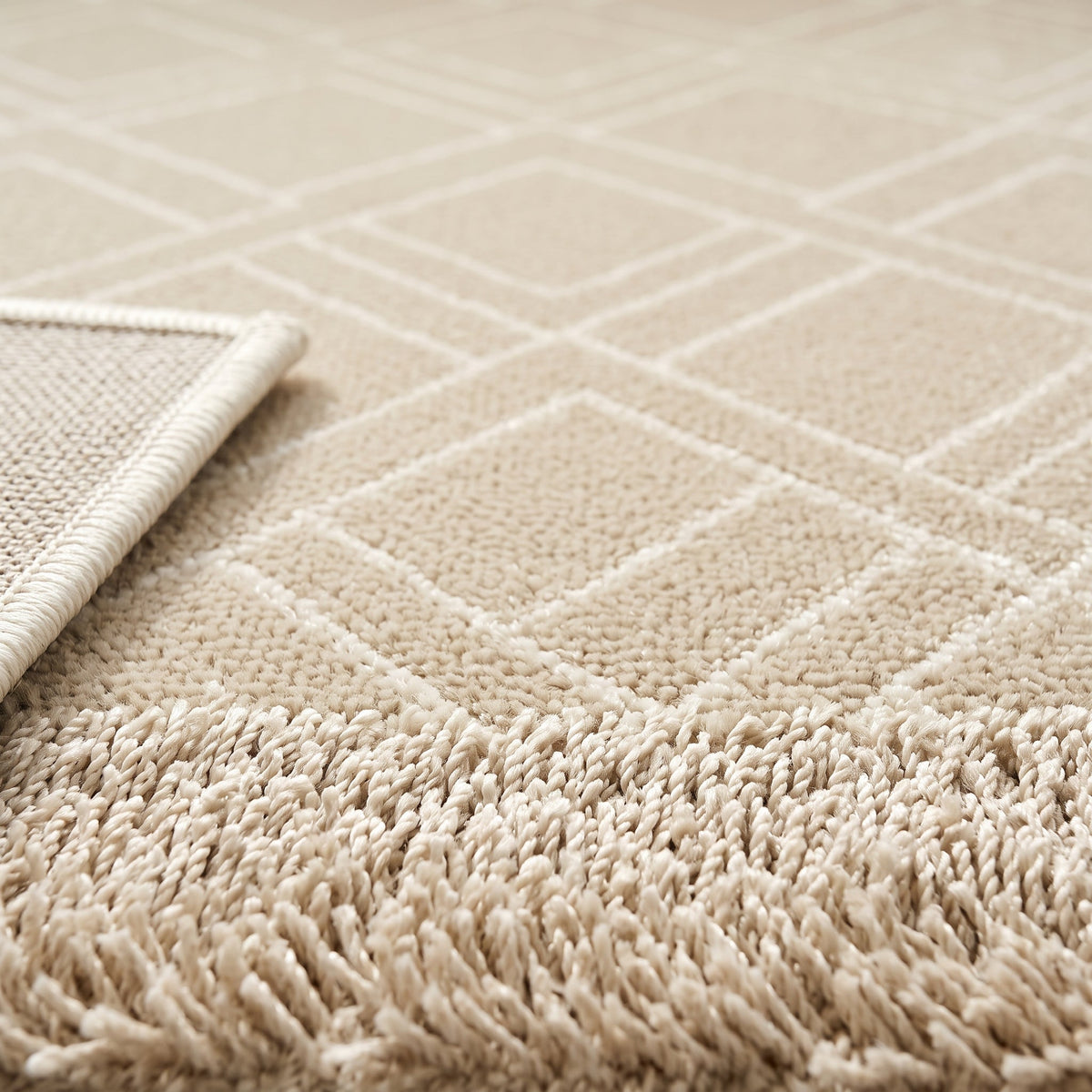 Gros plan sur le motif géométrique ton sur ton et les poils courts du tapis crème
